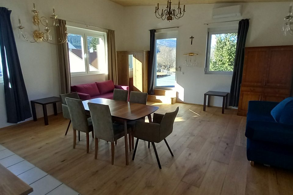 Esstisch mit sechs Stühlen, Schlafsofa und Fenstern zu den Hügeln